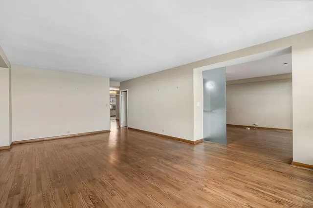 a view of an empty room and wooden floor and closet