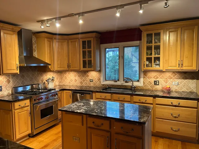 a kitchen with granite countertop wooden cabinets stainless steel appliances a sink and a window