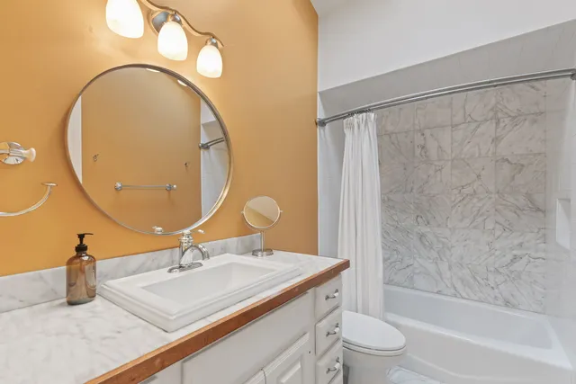 a bathroom with a granite countertop sink mirror vanity and toilet