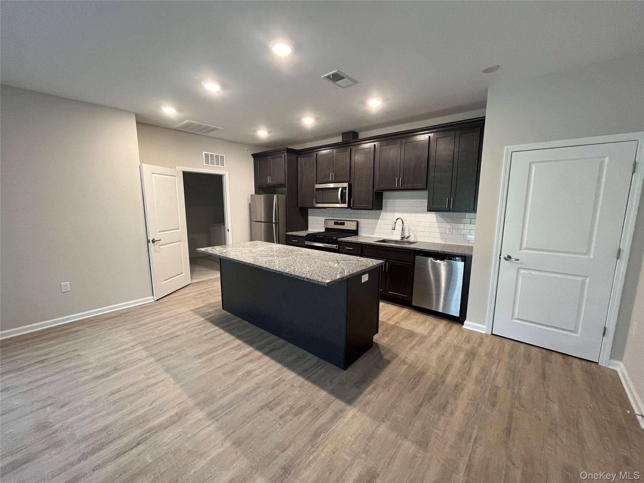 414 Tower Ridge Circle Middletown, NY 10941 - Photo 2 of 13 Tower Ridge Grande – Elegant open-concept kitchen with a spacious center island, stainless steel appliances, upscale cabinetry, recessed lighting, and luxury plank flooring. Designed for both style and functionalit