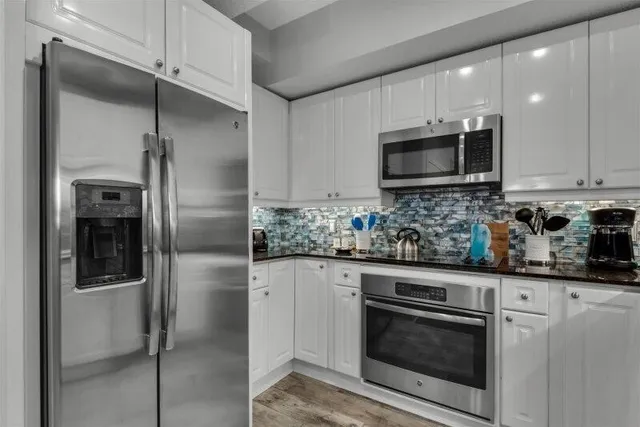 a kitchen with stainless steel appliances granite countertop a stove a refrigerator and a microwave