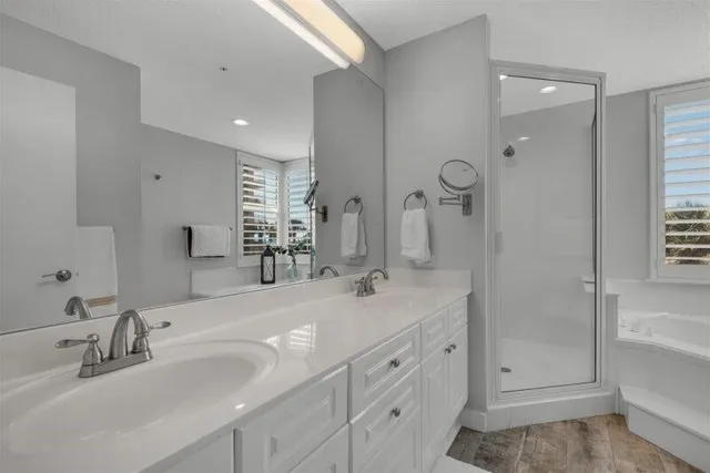 a bathroom with double vanity sink and mirror with bathtub