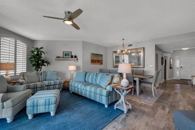 a living room with furniture a ceiling fan a lamp and a window