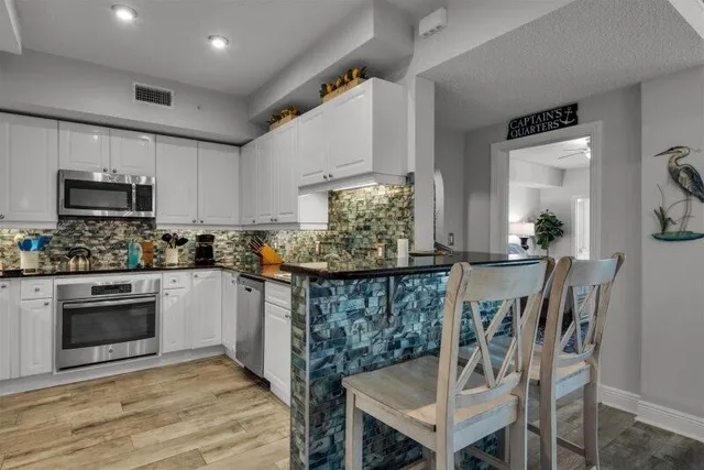 a kitchen with stainless steel appliances a dining table chairs stove and cabinets