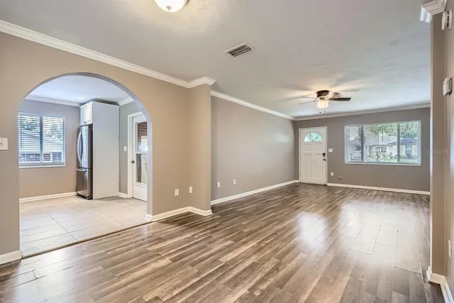 an empty room with wooden floor and windows