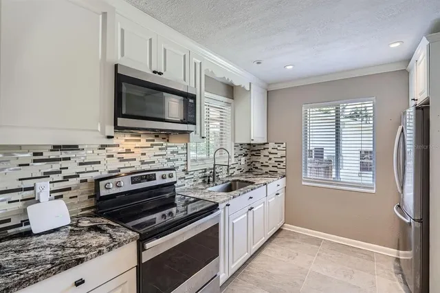 a kitchen with granite countertop a stove sink and microwave
