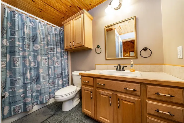a bathroom with a granite countertop sink mirror vanity and toilet