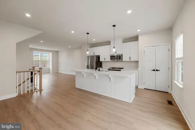 a view of kitchen with cabinets wooden floor and stainless steel appliances