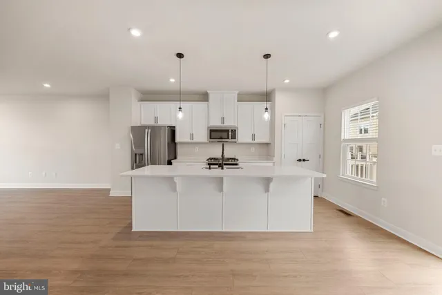 a view of kitchen with stainless steel appliances granite countertop a sink a stove a refrigerator and white cabinets