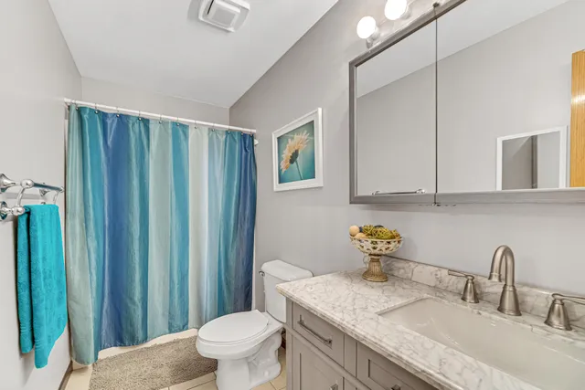 a bathroom with a granite countertop sink a toilet and mirror