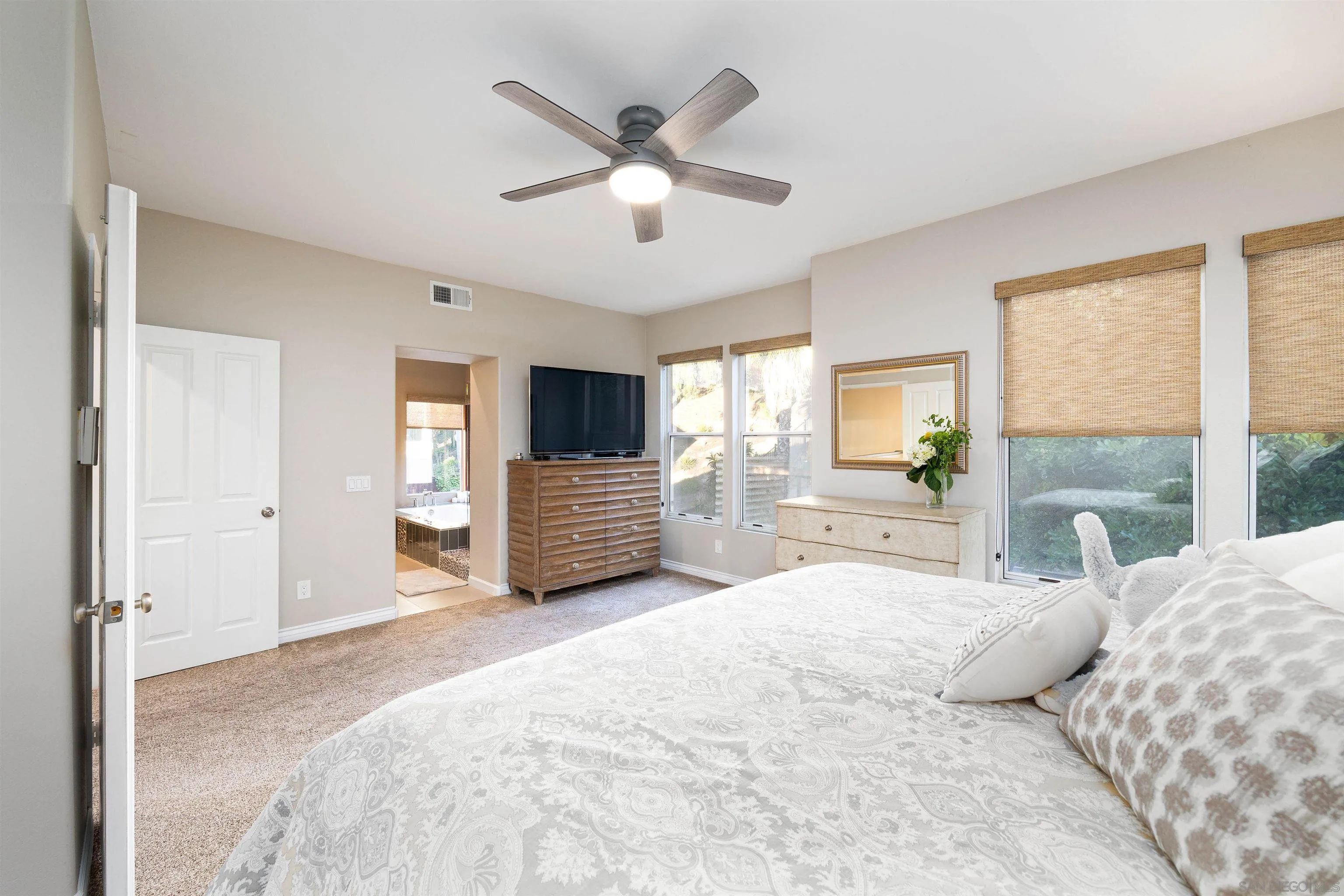 13835 Carmel Ridge Road San Diego, CA 92128 - Photo 16 of 38 a spacious bedroom with a large bed and a chandelier