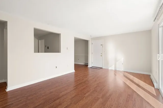 a view of an empty room with wooden floor and a window