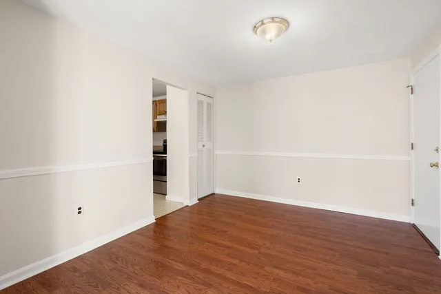 a view of an empty room with wooden floor and closet