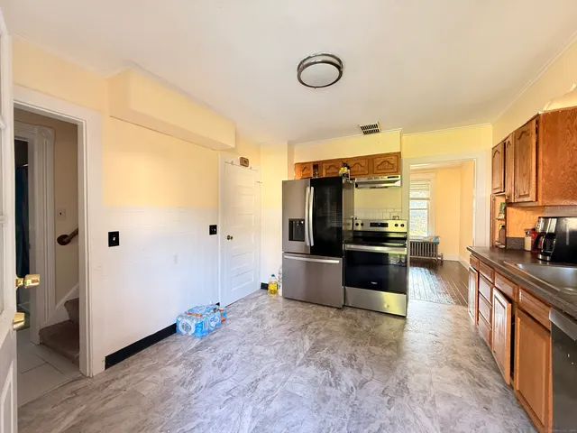 a large living room with stainless steel appliances furniture a rug and a kitchen view