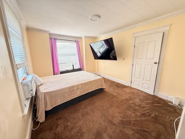 a bedroom with a bed a flat screen tv and dresser