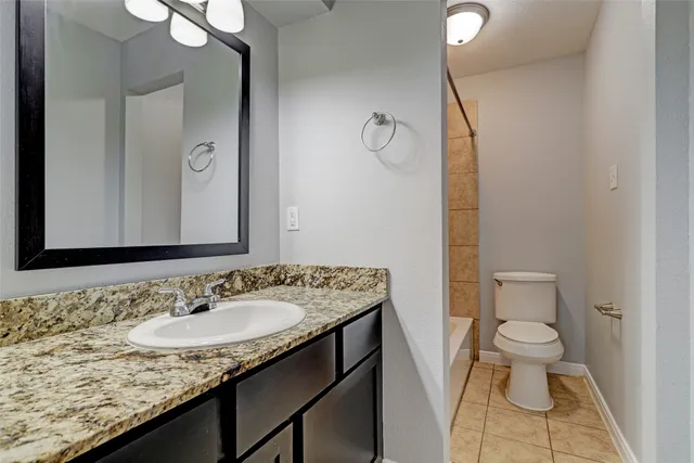 a bathroom with a granite countertop sink a toilet and a mirror