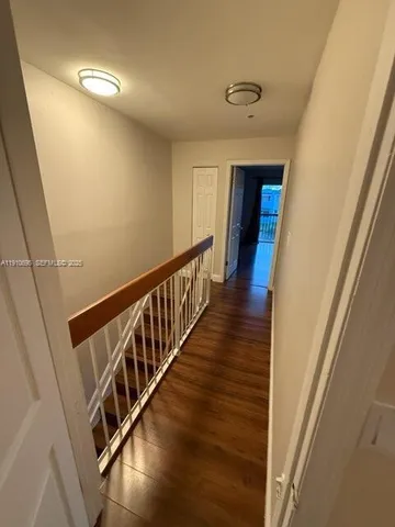 a view of a hallway with wooden floor and staircase