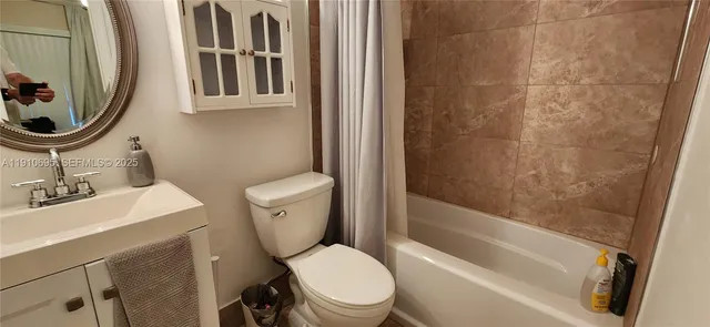 a white toilet sitting next to a bathroom sink and a tub