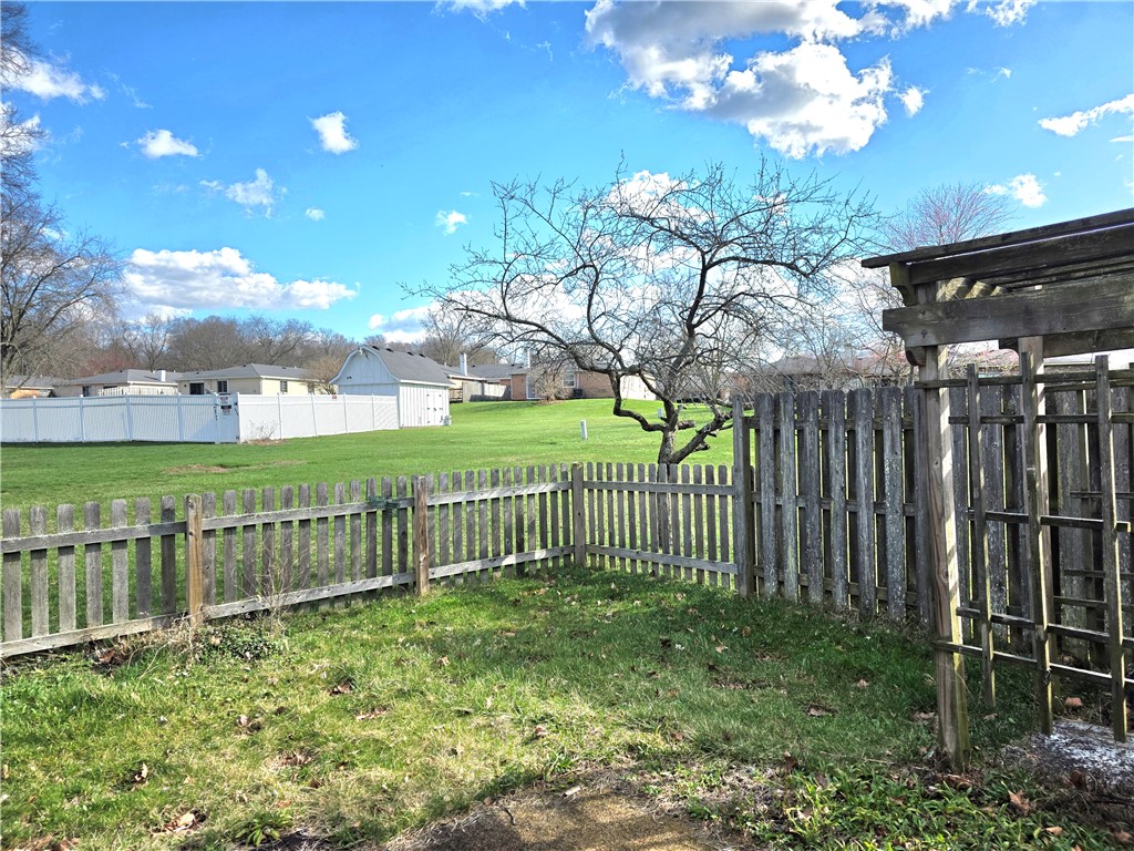 9920 Sheehan Road Dayton, OH 45458 - Photo 40 of 46 This expansive backyard features lush green grass and a charming wooden fence, offering a private outdoor retreat.