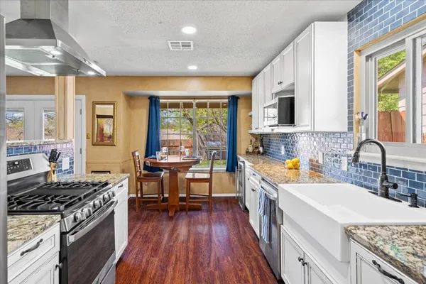 a kitchen with a stove a sink and wooden cabinets