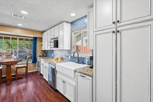 a kitchen with a sink appliances wooden floor and a window