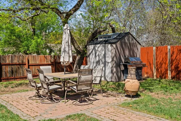 a view of a backyard with table and chairs potted plants and a large tree