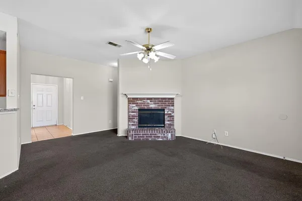 an empty room with a fireplace and a ceiling fan
