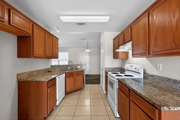a kitchen with stainless steel appliances granite countertop wooden cabinets a stove top oven a sink and dishwasher
