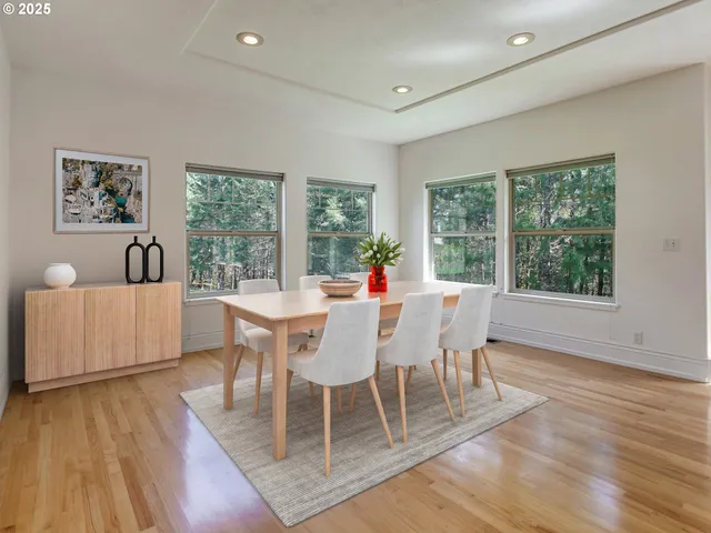 a dining room with wooden floor and large windows