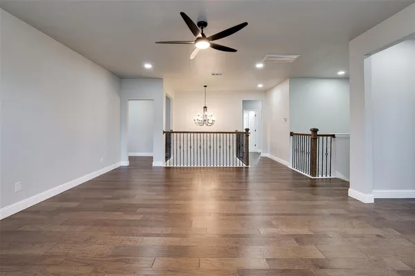 a view of an empty room with kitchen and a chandelier fan
