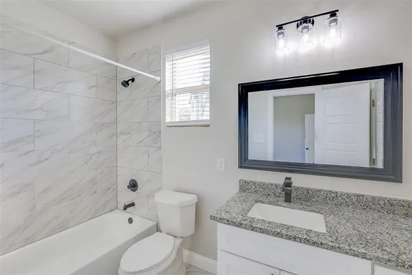a bathroom with a granite countertop sink mirror vanity and toilet