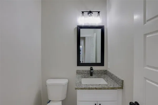 a bathroom with a granite countertop toilet sink and mirror