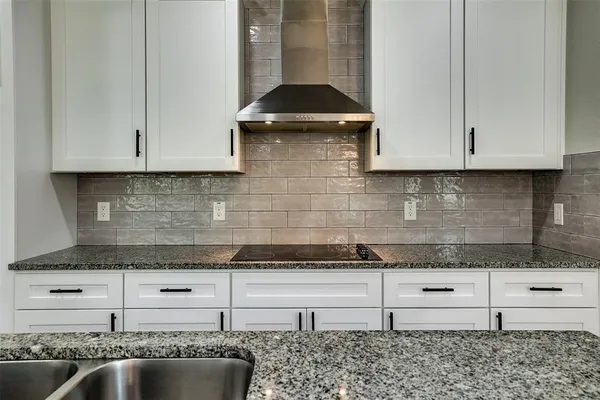 a kitchen with granite countertop white cabinets and a stove