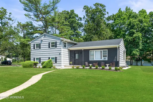 a front view of a house with a garden and trees
