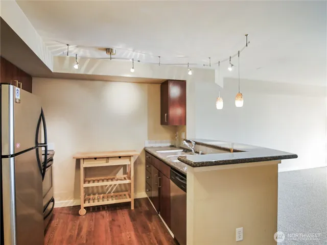 a kitchen that has a sink stainless steel appliances wooden floor and cabinets
