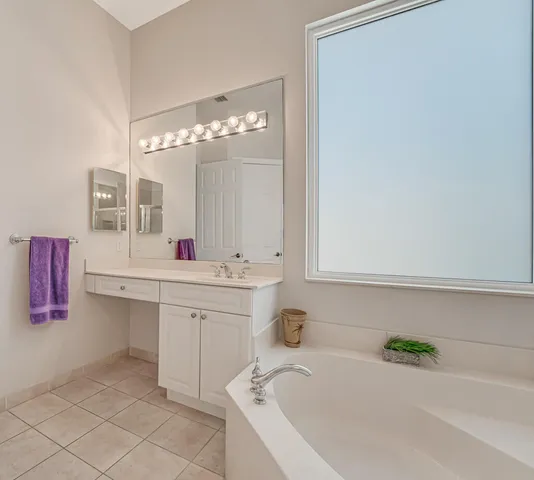 a bathroom with a tub a sink double vanity and a mirror