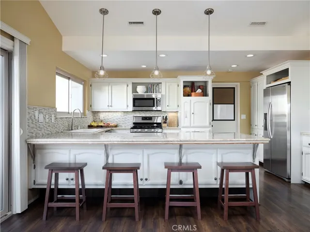 a kitchen with kitchen island a dining table chairs and white cabinets