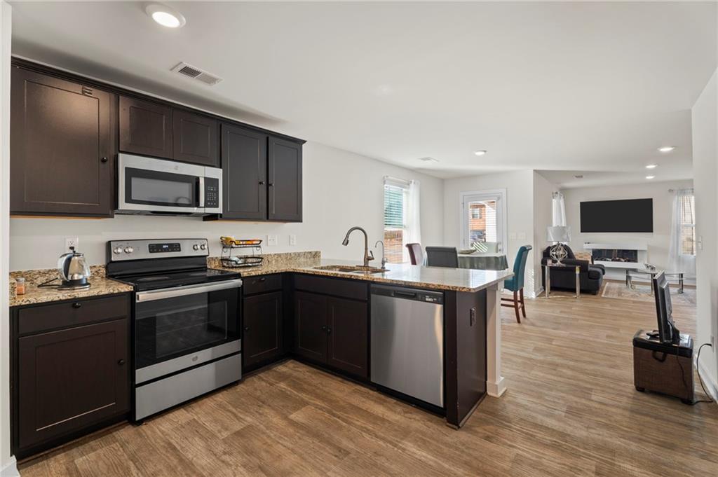 1149 Bluecoat Circle Hampton, GA 30228 - Photo 6 of 21 a kitchen with stainless steel appliances kitchen island granite countertop a stove top oven and sink