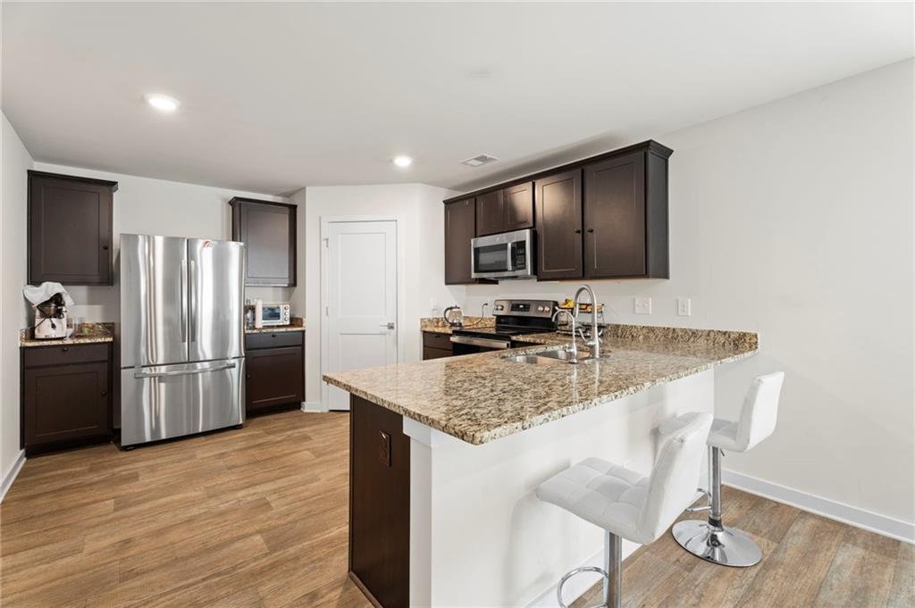 1149 Bluecoat Circle Hampton, GA 30228 - Photo 7 of 21 a kitchen with stainless steel appliances granite countertop a sink refrigerator and microwave