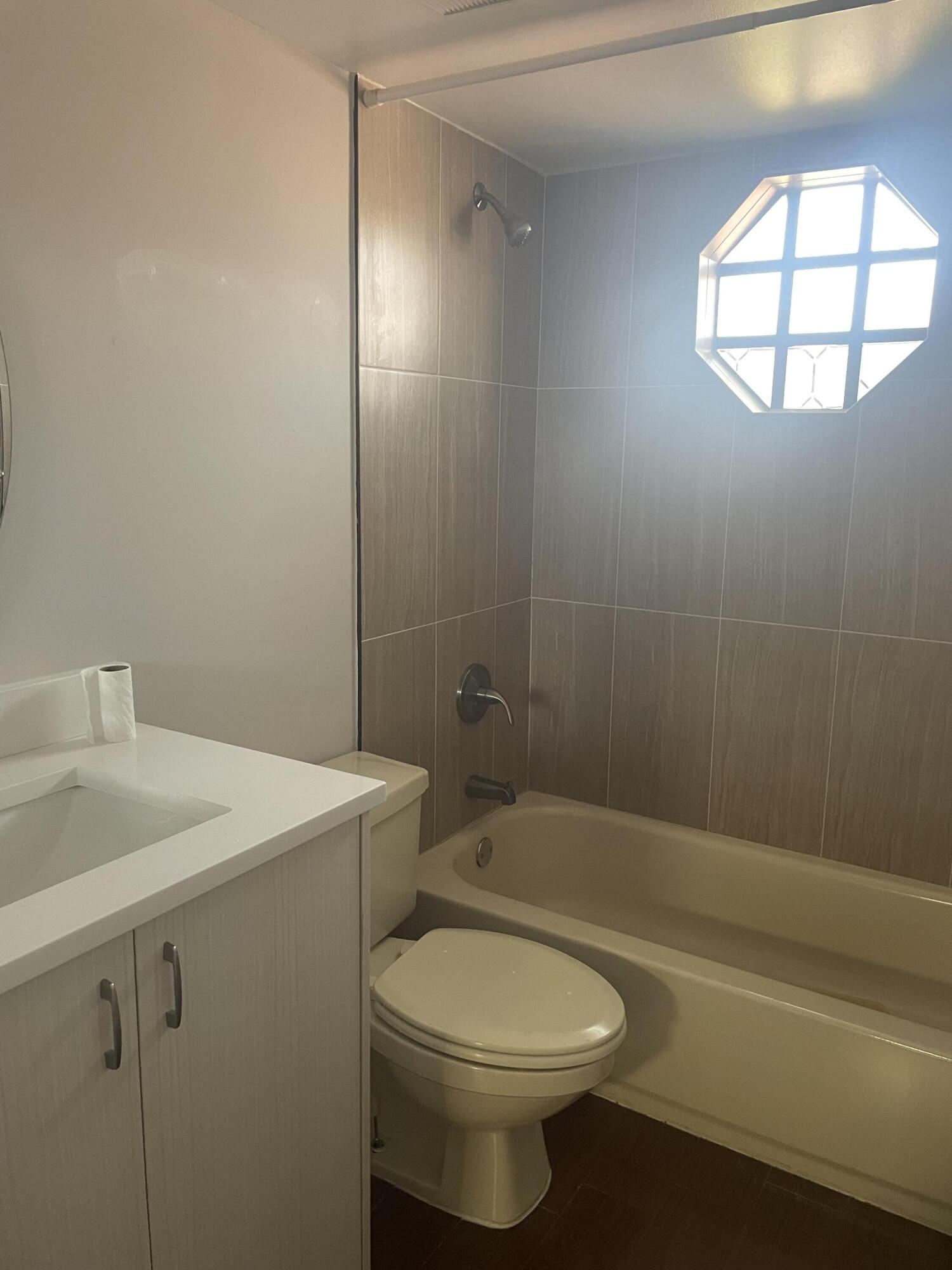 18258 Covina Way, Unit 102 Boca Raton, FL 33498 - Photo 12 of 14 a bathroom with a sink a toilet and shower
