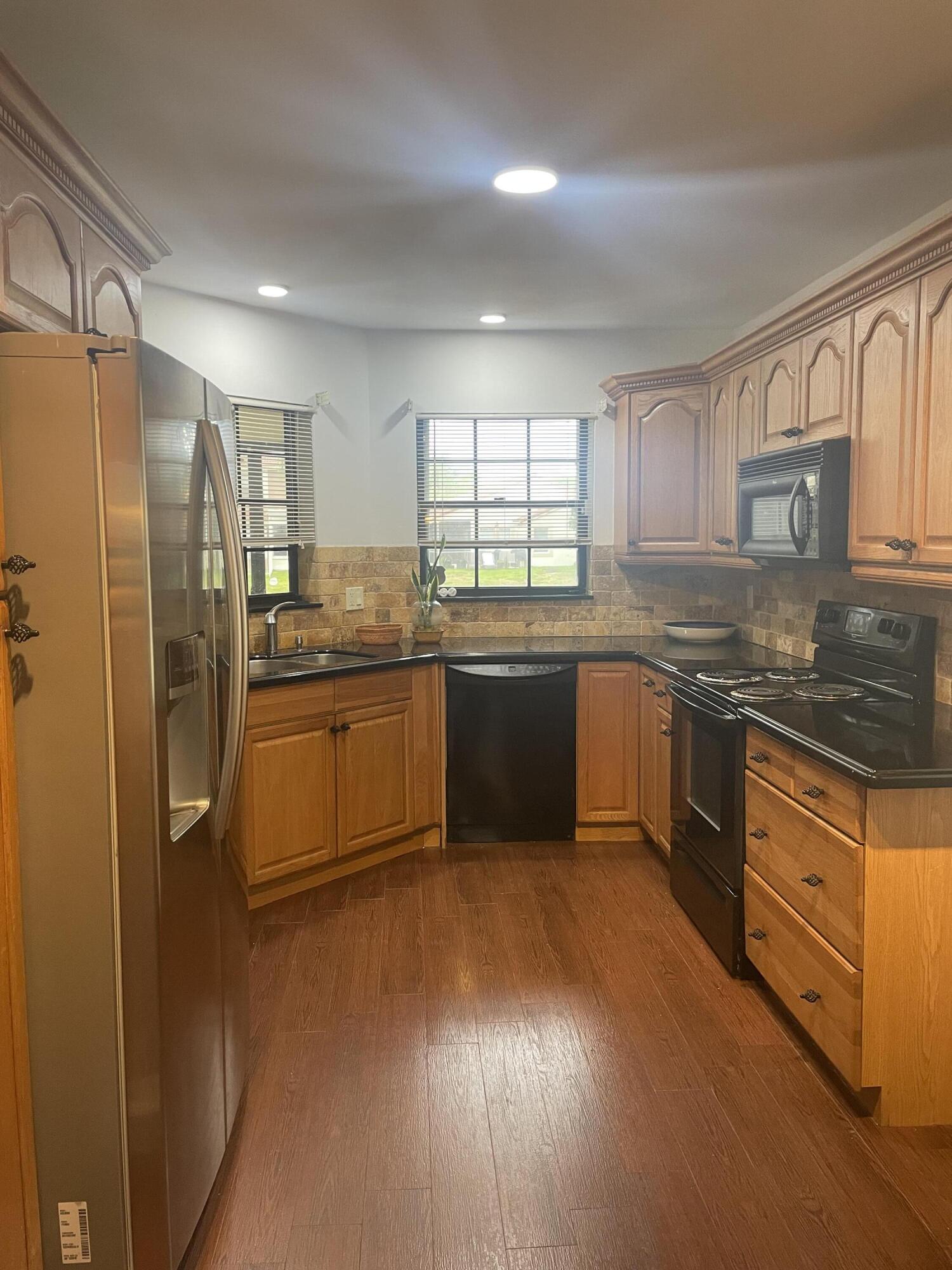 18258 Covina Way, Unit 102 Boca Raton, FL 33498 - Photo 3 of 14 a kitchen with stainless steel appliances granite countertop a stove a sink dishwasher a refrigerator and white cabinets with wooden floor