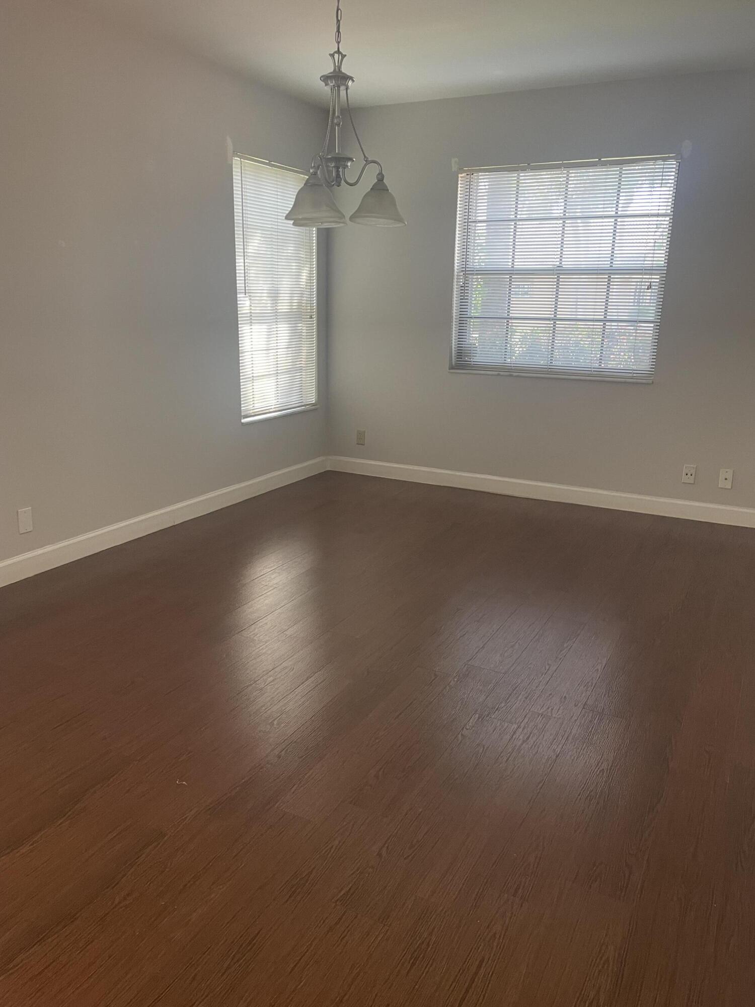 18258 Covina Way, Unit 102 Boca Raton, FL 33498 - Photo 5 of 14 an empty room with wooden floor and windows