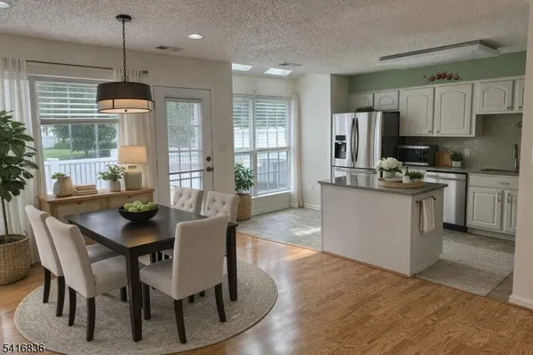 a living room with stainless steel appliances granite countertop furniture wooden floor and a kitchen view