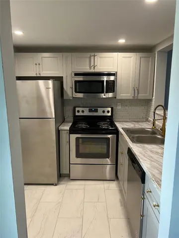 a kitchen with stainless steel appliances granite countertop a refrigerator stove a sink and microwave