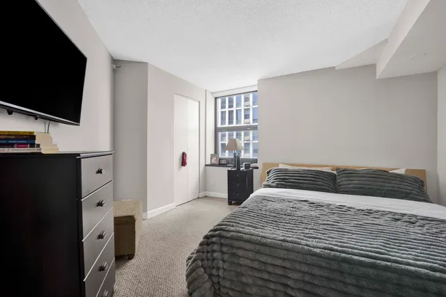 a bedroom with a large bed and a flat tv screen on dresser