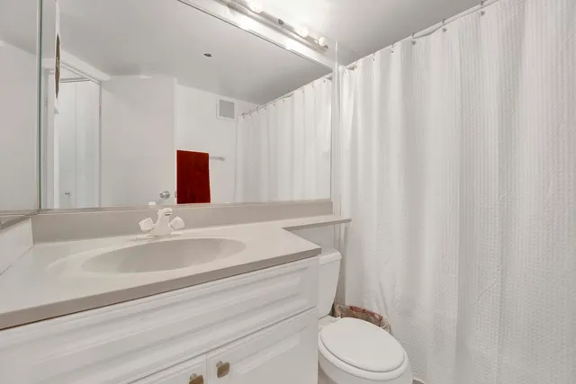 a bathroom with a sink vanity mirror and toilet