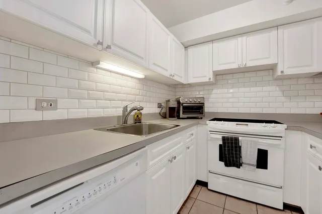 a kitchen with granite countertop white cabinets and white appliances
