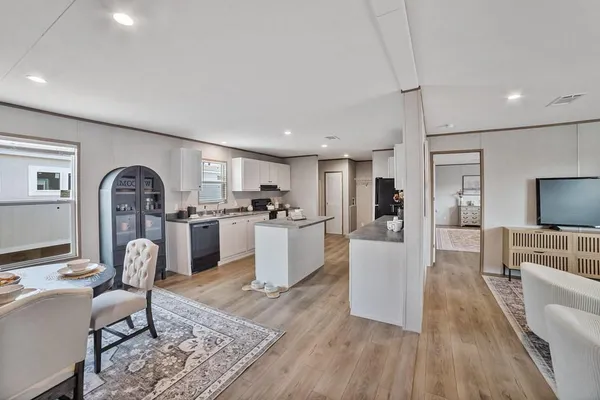 a living room with furniture a flat screen tv and a refrigerator