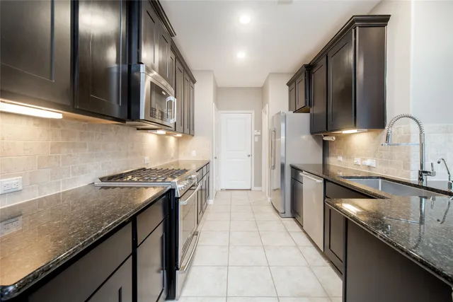 a kitchen with stainless steel appliances granite countertop a refrigerator and a stove