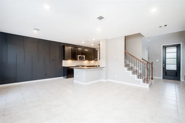 a view of an empty room with kitchen and a window